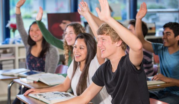 Classe di studenti che alza la mano durante una lezione.
