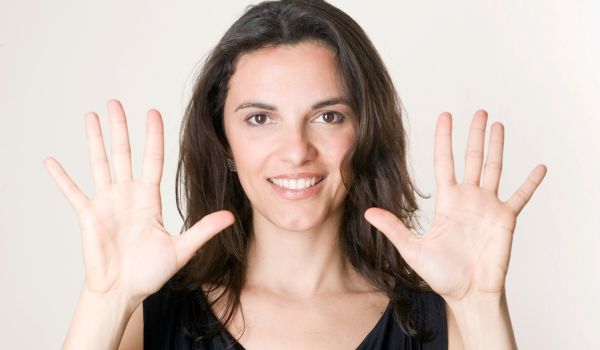 Una donna che mostra il numero dieci con le dita delle due mani.